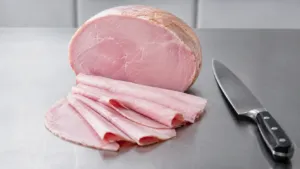 Jambon blanc cuit tranche sur un plan de travail neutre