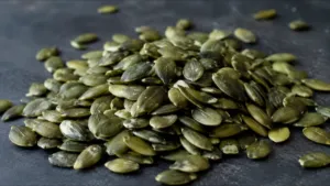 Tas de graines de courge décortiquées vertes sur une surface sombre