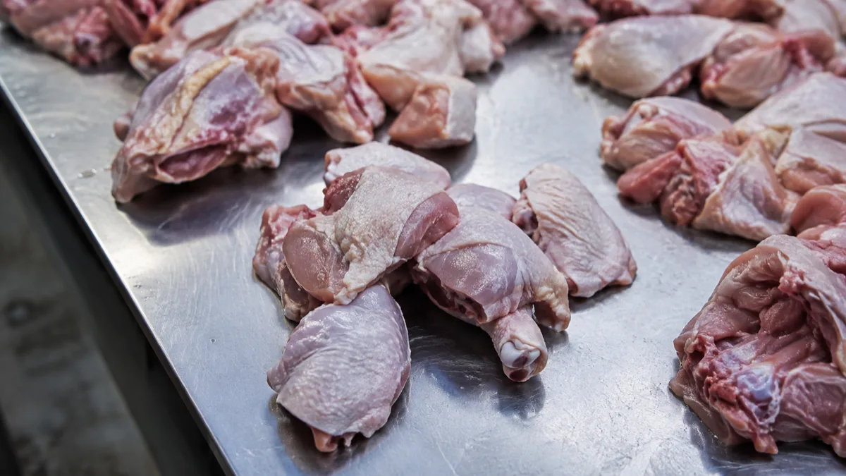 Morceaux de poulet cru posés sur un plan de travail en inox